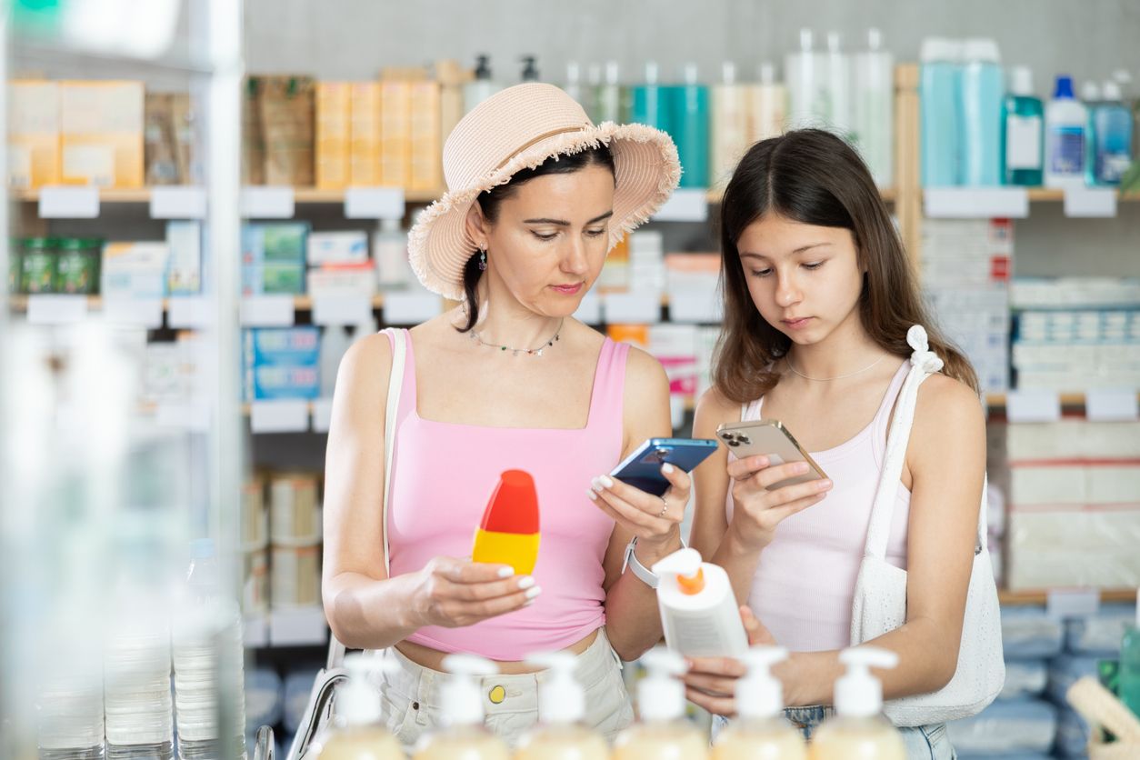 Frau mit Kind scannt Paket mit Sonnencreme in der Apotheke