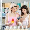 Frau mit Kind scannt Paket mit Sonnencreme in der Apotheke