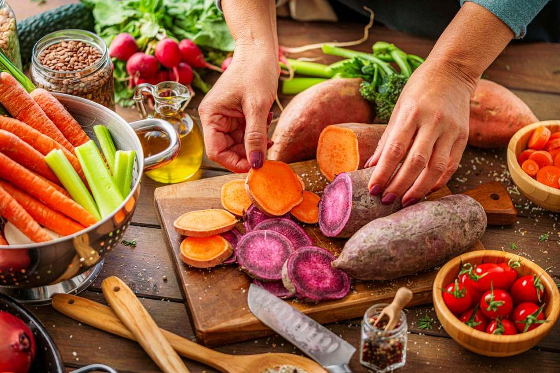 Köchin schneidet zu Hause Wurzelgemüse. Zubereitung nahrhafter vegetarischer Speisen 