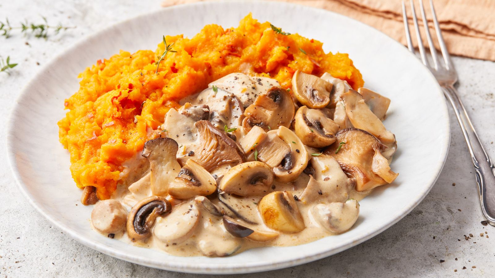 Kürbispüree mit gebratenen Pilzen an Sahnesauce auf einem Teller serviert