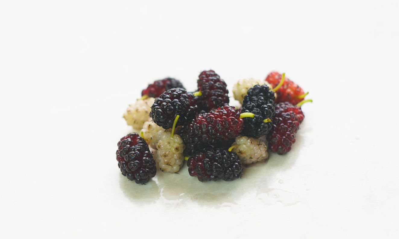 Ein Haufen weißer und roter Maulbeeren auf einem weißen Marmortisch