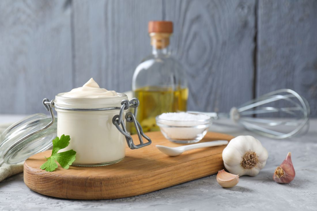 Leckere Mayonnaise im Glas und Zutaten auf grauem Tisch