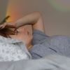 Frau liegt mit Migräne im Bett