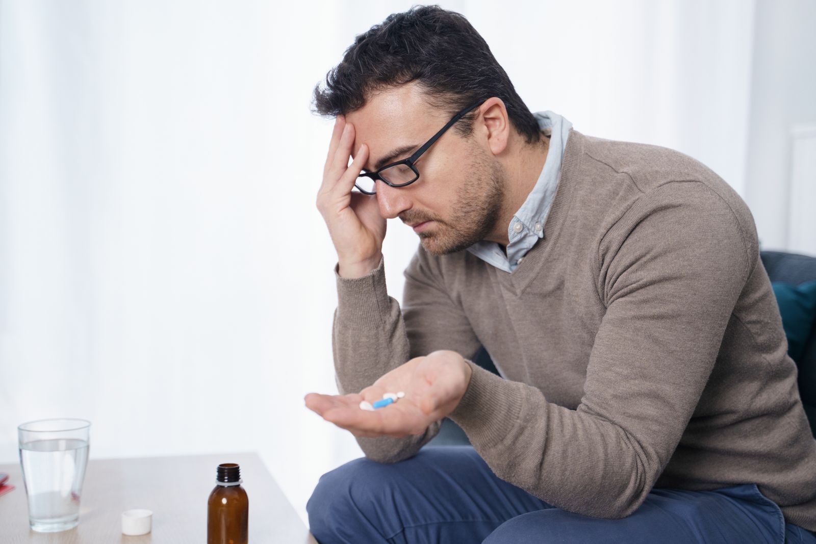 Mann mit Kopfschmerzen nimmt Vitamin B1