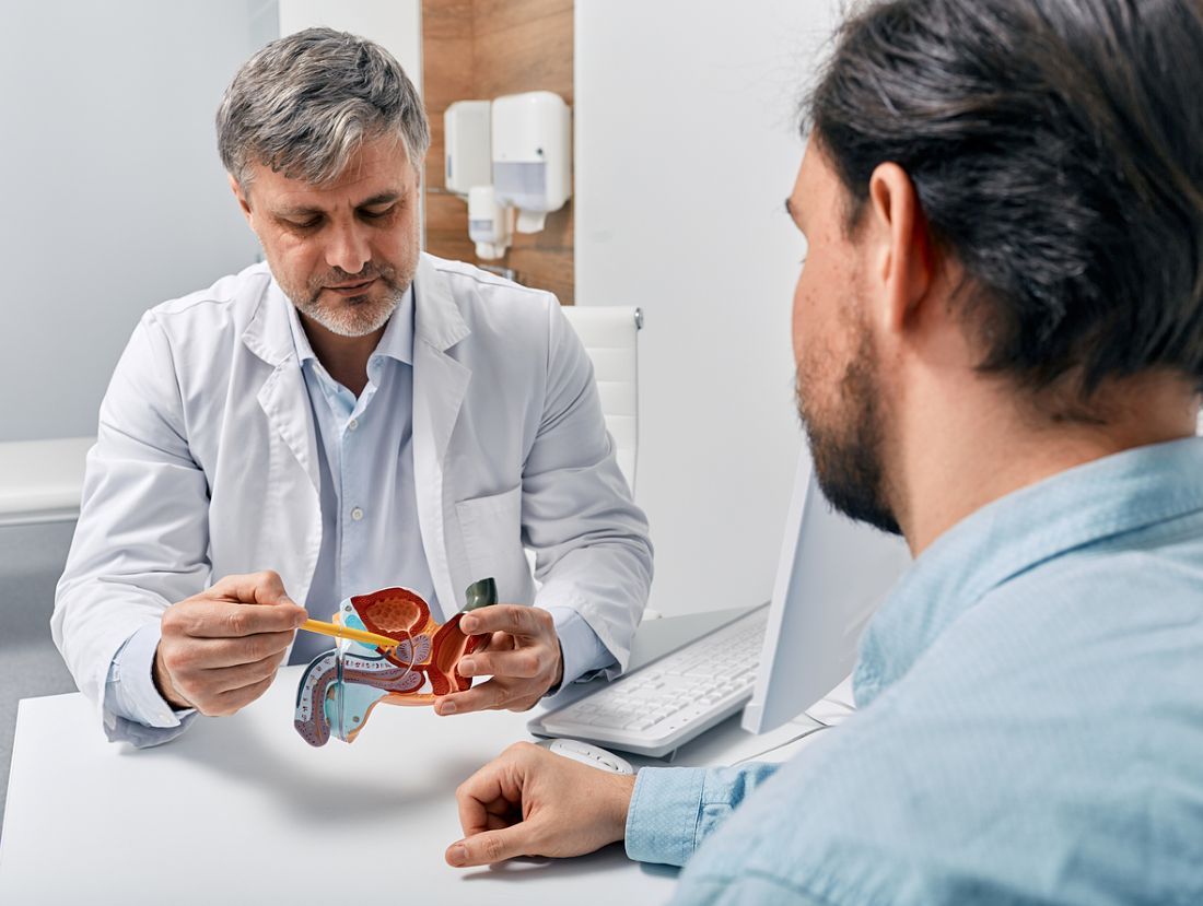  Urologe, der Patienten mit Prostatitis berät, erklärt ihm Behandlungsmethoden anhand des anatomischen Modells des männlichen Fortpflanzungssystems. Behandlung von Prostatitis