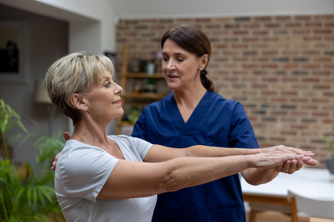 Seniorin, die zu Hause mit einem Physiotherapeuten Physiotherapie macht