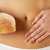 Frau hält Brot und fasst sich den Bauch an