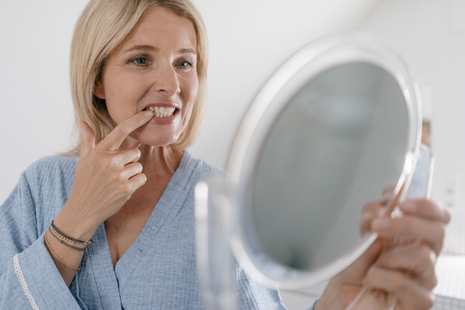 Frau schaut ihr Zähne an im Spiegel