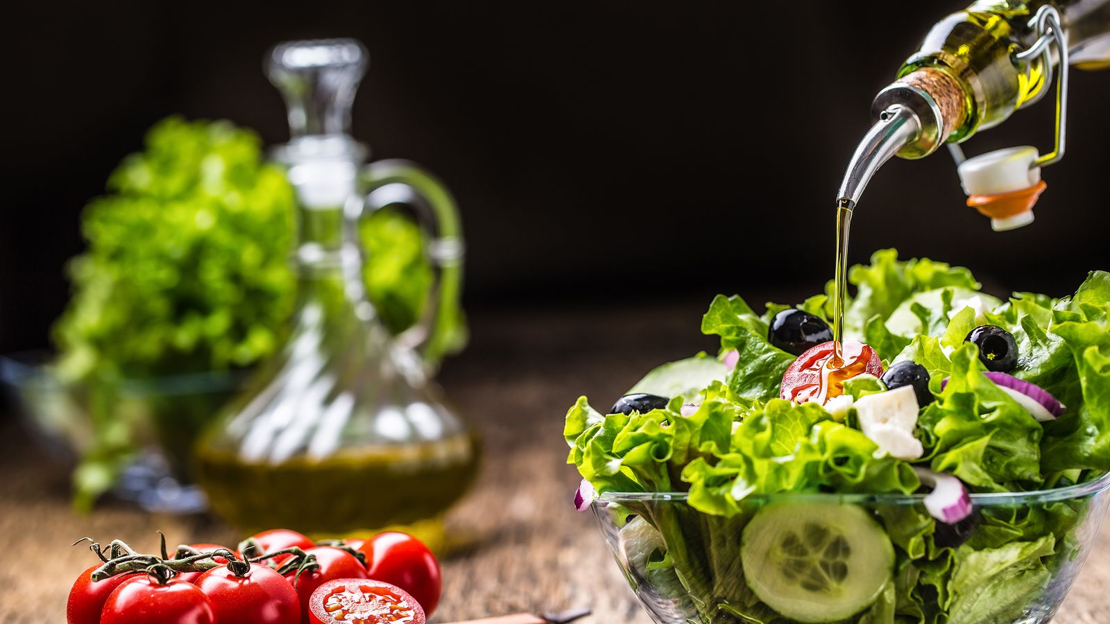 Frischer Salat wird mit Olivenöl angerichtet