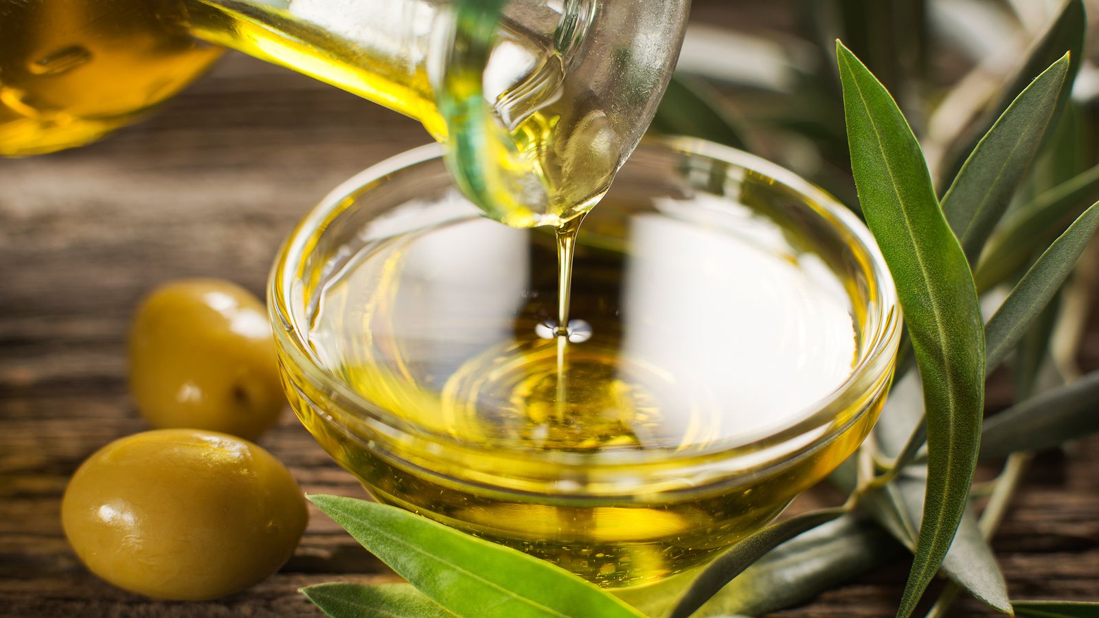 Olivenöl fliesst in ein Glas