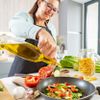 Frau nimmt Olivenöl für das Gemüsegericht