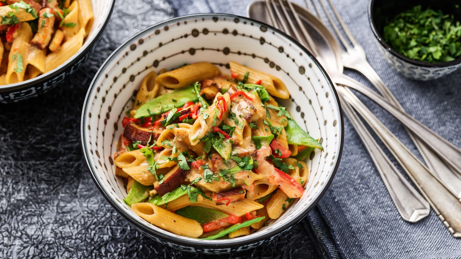 One Pot – mit Penne, Gemüse und Tofu, pikant abgeschmeckt und mit Koriander bestreut in einer weissen Schüssel serviert