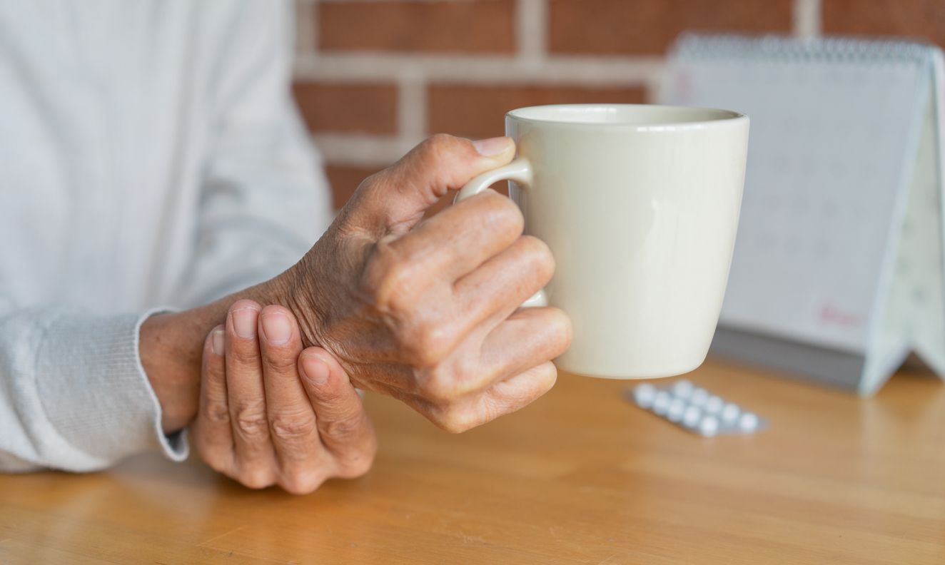 Mann mit Parkinson hält eine Kaffeetasse