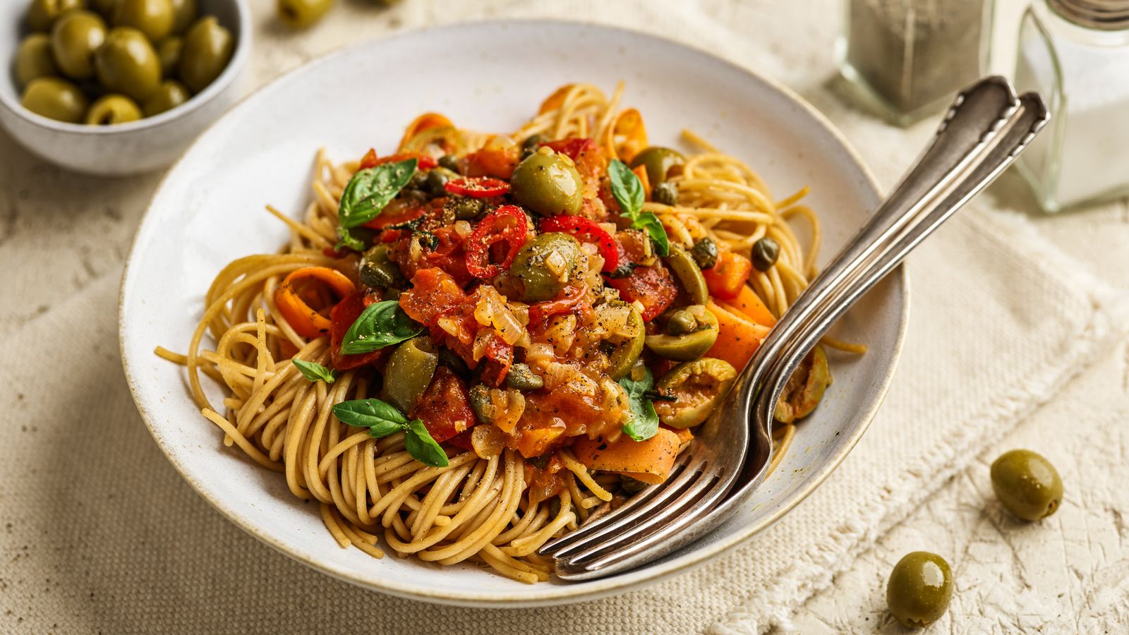 Pasta alla puttanesca auf einem weissen Teller