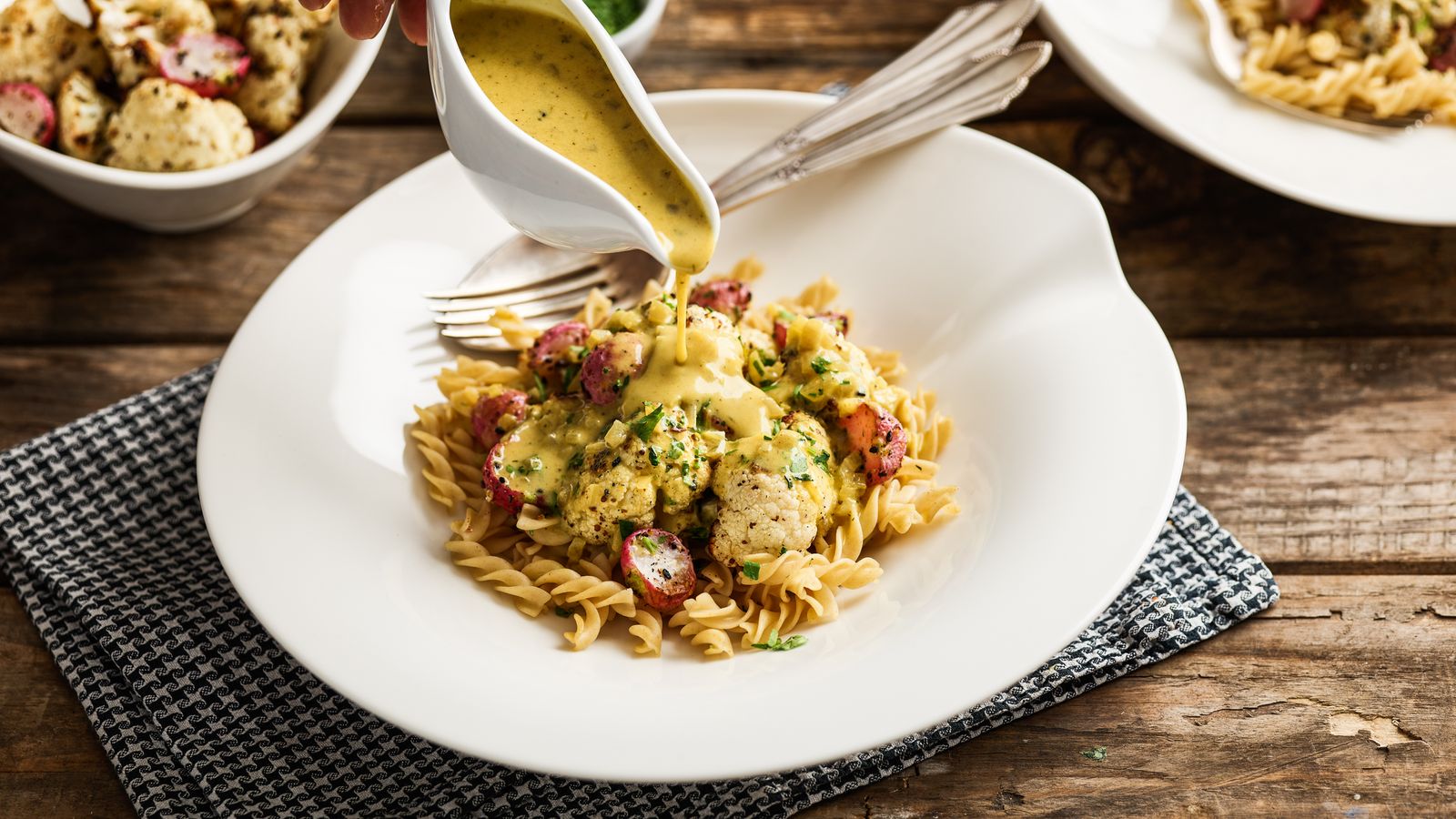 Pasta mit Blumenkohl an Currysauce auf einem weissen Teller