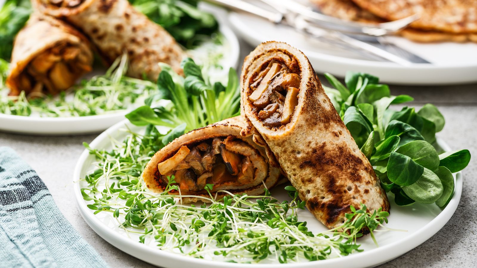 Köstliche Pfannkuchen mit einer Pilzragout-Füllung auf einem weissen Teller serviert