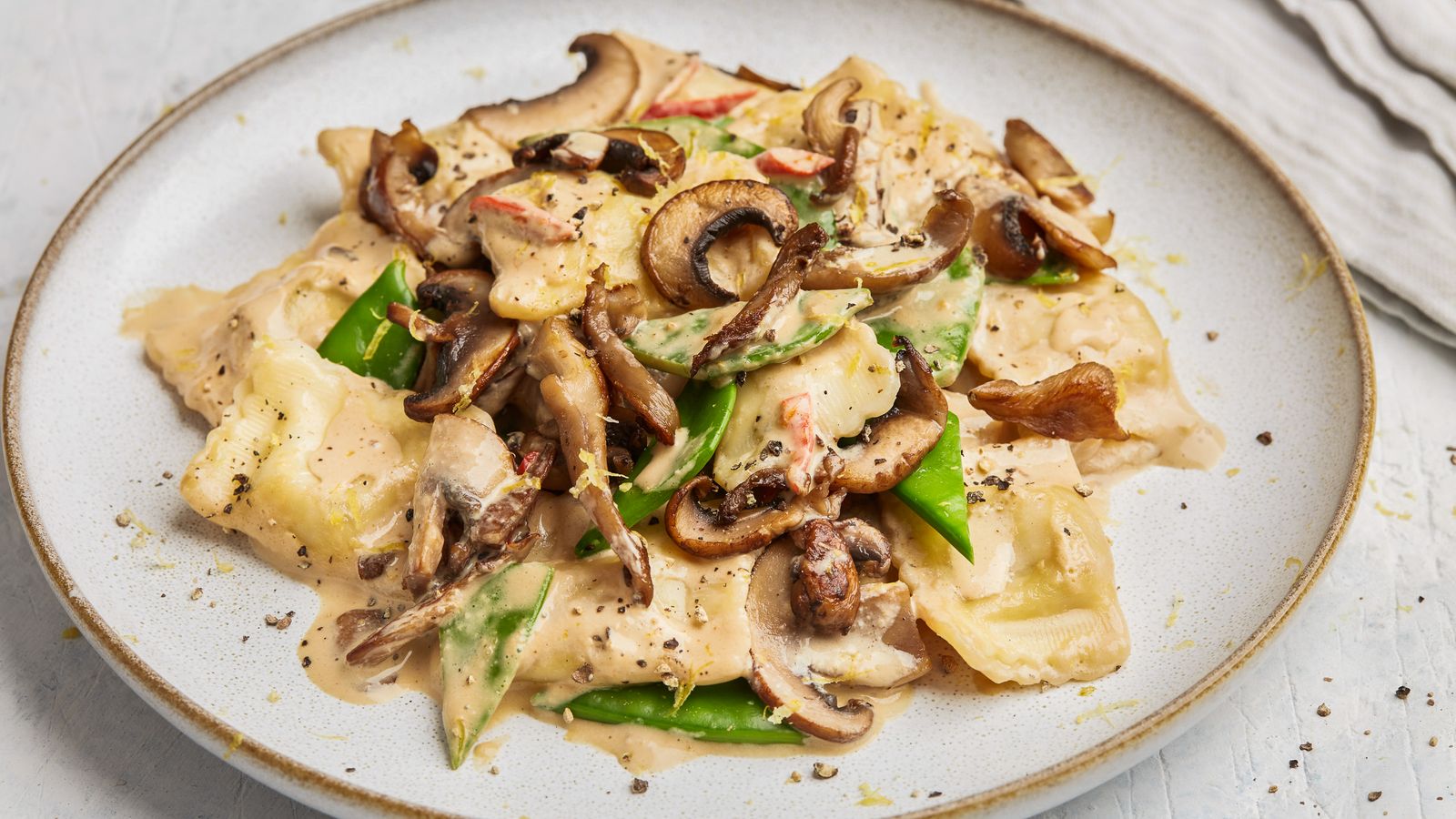 Ravioli mit cremiger Pilzsauce auf einem Teller angerichtet