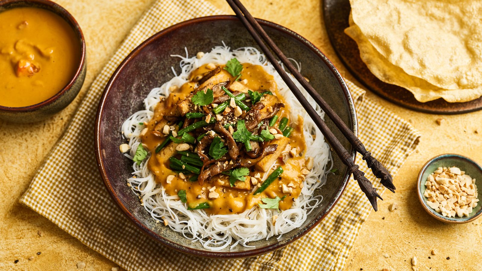 Reisnudeln mit Tofu-Pilzgemüse an Süsskartoffelsauce in einer dunkeln Schale serviert