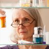 Ältere Frau liest sich die Rückseite Ihrer Magenschutzmedikamente durch