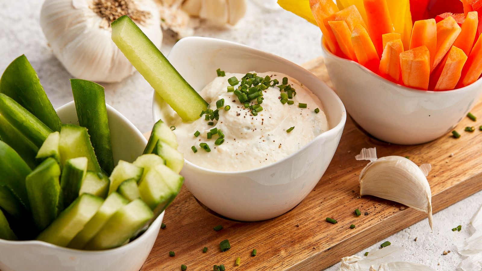 Sauerrahm-Dip mit Knoblauch in einer Schüssel mit Gurken und Karotten