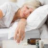Frau schläft in Ihrem Bett, im Vordergrund Schlafmittel