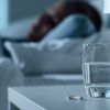 Frau liegt im Bett Schlaftabletten auf dem Nachttisch