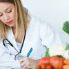 Ärztin füllt ein Formular über gesunde Ernährung aus. Im Vordergrund: Gemüse