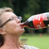 Ältere Frau trink aus einer Cola-Flasche