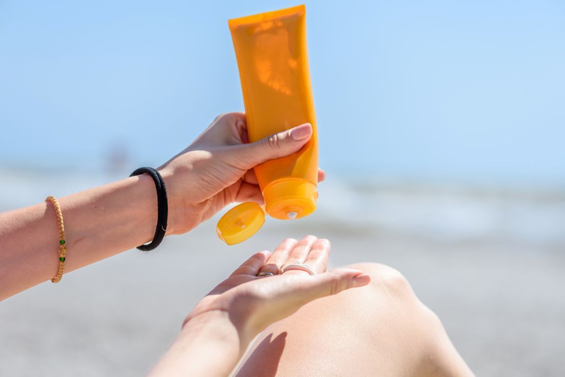 Eine Frau hält Flaschen mit Sonnencreme in den Händen