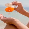 Frau cremt sich mit Sonnencreme ein