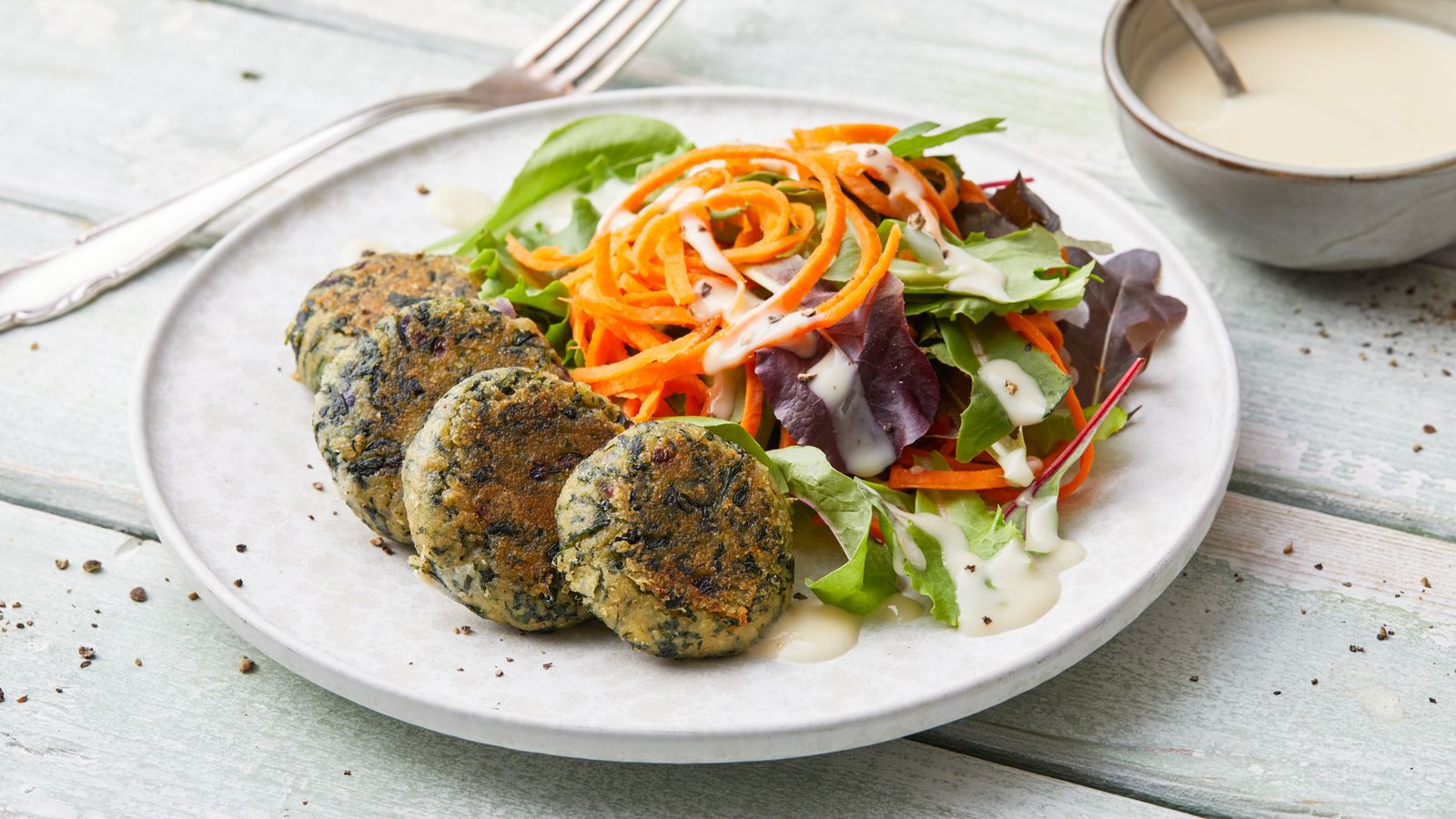 Spinatbratlinge mit Joghurt-Tahini-Sauce auf einem Teller