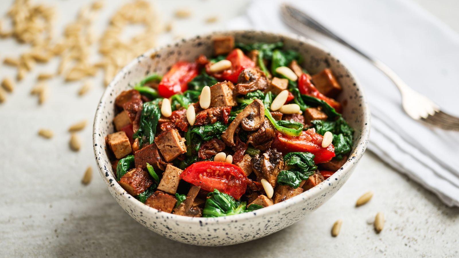 Spinat mit Tomaten und geräuchertem Tofu in einer Schüssel serviert