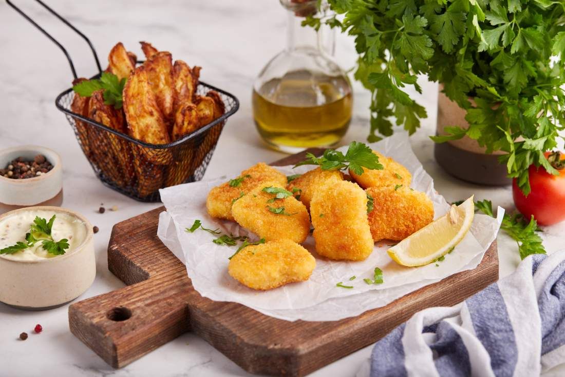 Fischnuggets serviert mit Kartoffelspalten und Sauce