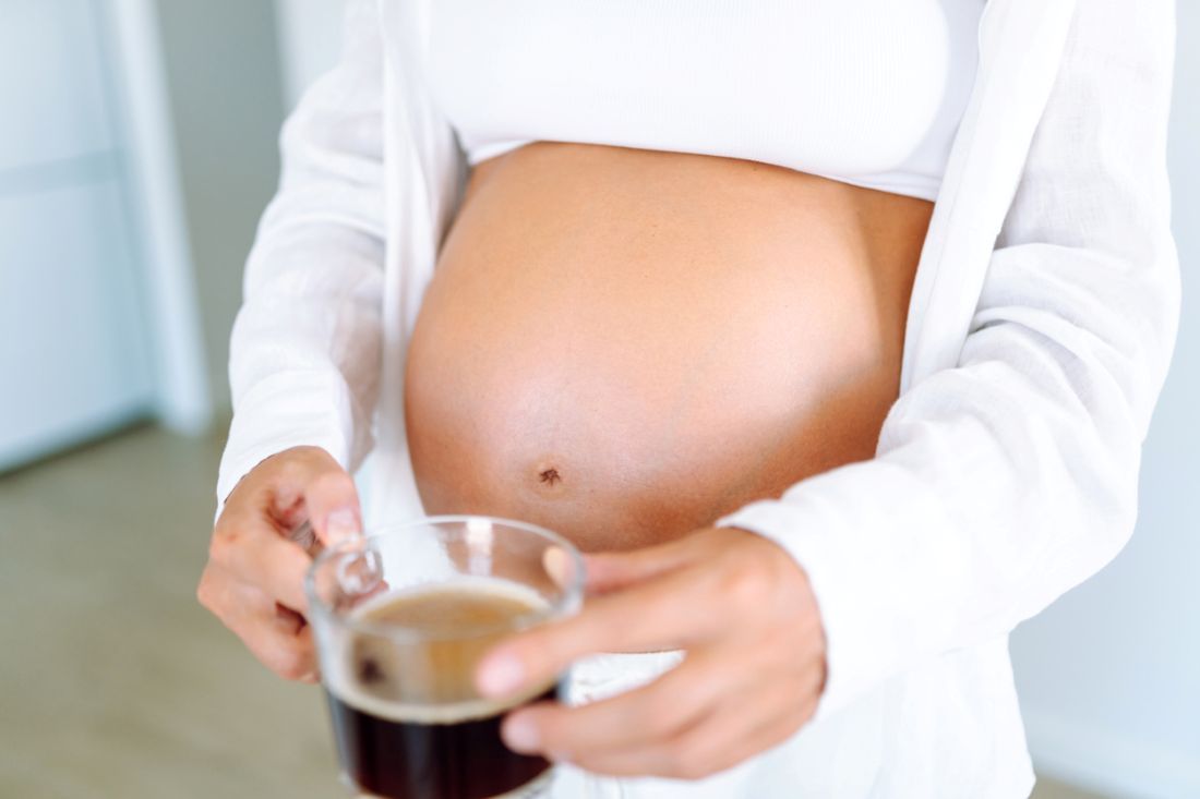 Schwangere Frau, die eine Tasse Kaffee hält