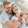 Glückliches und liebevolles reifes kaukasisches Paar, das an einem sonnigen Tag zusammen ein romantisches Date am Strand genießt