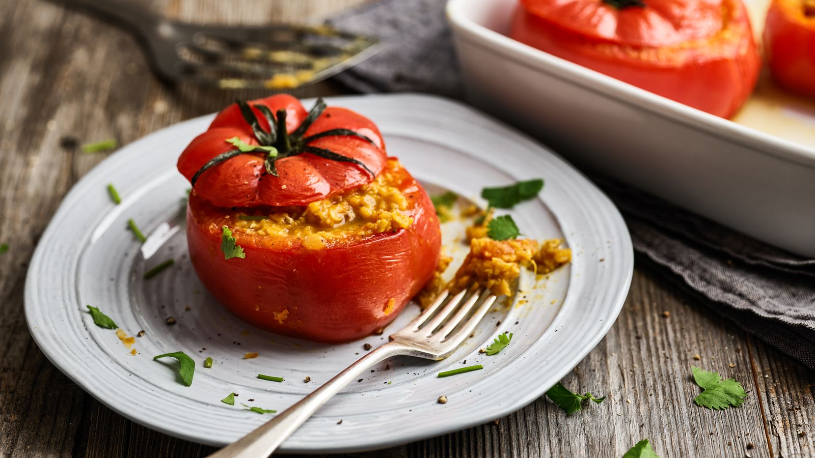 Tomaten mit indischer Linsenfüllung serviert auf hellgraum Teller