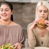 Zwei Frauen, eine isst gesund, die andere isst Fastfood