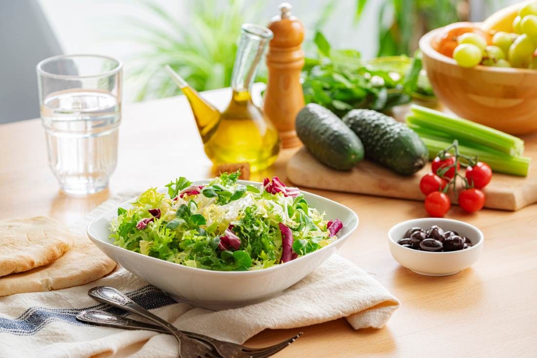 Frischer gemischter Salat, Salatschüssel und Zutaten auf dem Esstisch