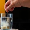 Frau wirft eine Brausetablette in ein Wasserglas